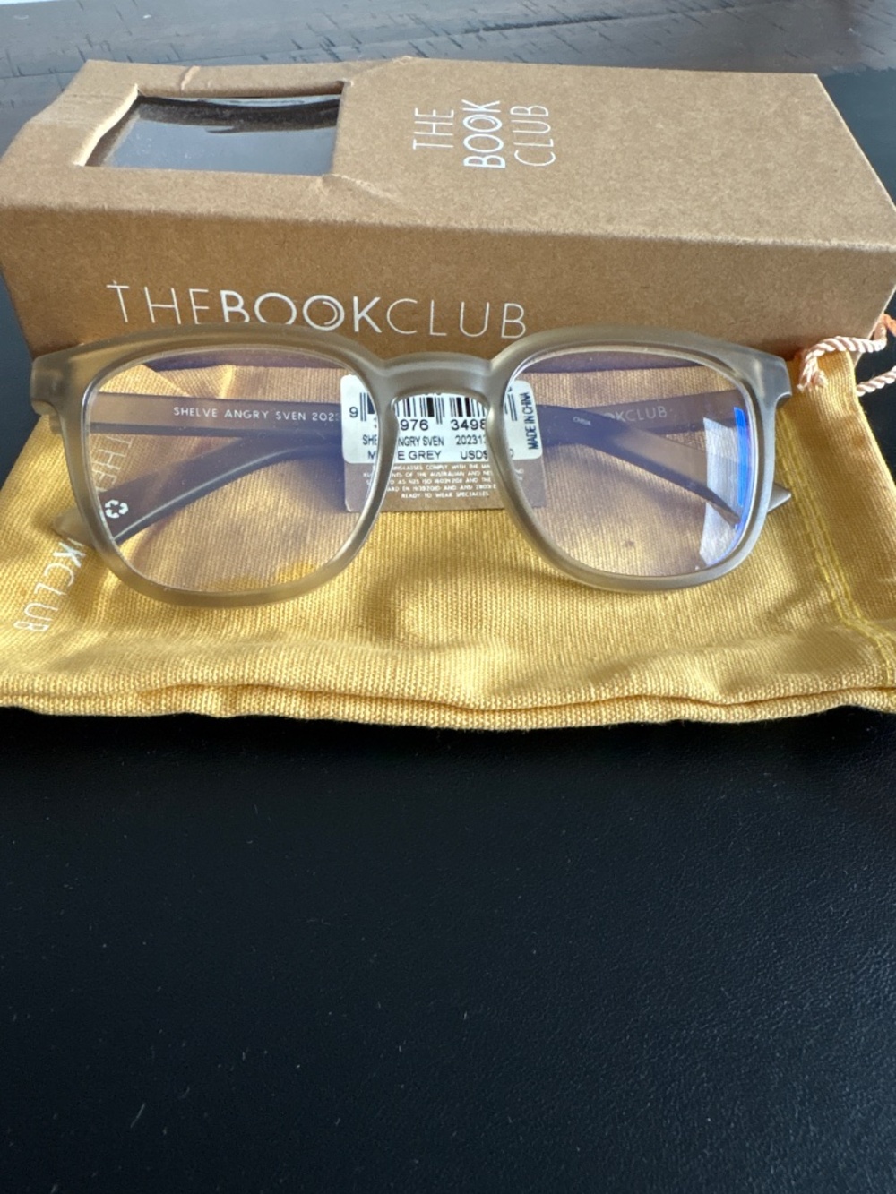 The Book Club matte crystal gray reading glasses with a square frame. +1.00